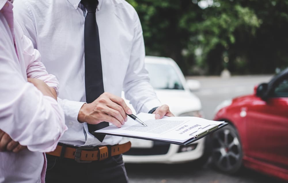 Traffic accident and insurance concept: An insurance agent reviews a report form while managing the car accident claim process.