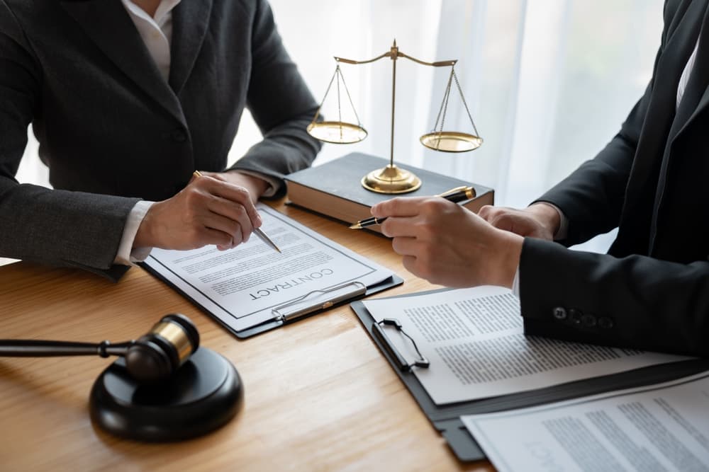 An Asian lawyer and legal advisor explaining contract details to a businessman and investors, discussing agreements while taking notes for accuracy. Business consultation concept.