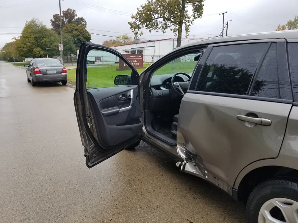 A rainy day car accident involving a four-door sedan and a minivan in a T-bone crash, with an insurance claim being processed.